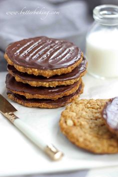 cookies with chocolate frosting are on a plate next to a glass of milk