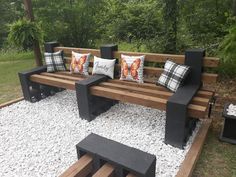 a wooden bench sitting on top of a gravel covered field next to trees and bushes