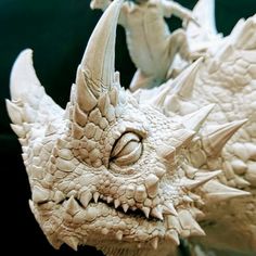 a close up of a toy dragon with two people in the background