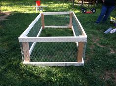 the chicken coop is made out of wood and wire, with two people standing in the background