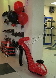 a pair of red high heeled shoes sitting next to a wall with black and red balloons