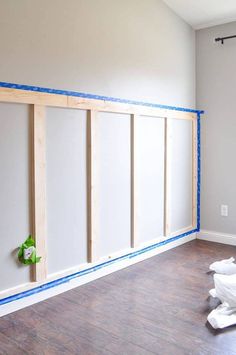 an empty room with white walls and blue tape on the wall next to wood flooring