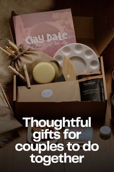 a box filled with lots of different items on top of a wooden table next to a cup