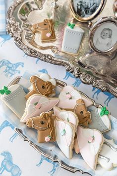 some cookies are on a silver tray near an old photo and other items in the background