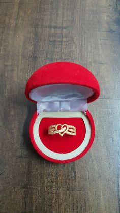 an open red velvet ring box with two gold rings in it on a wooden surface