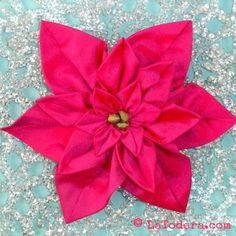 a pink flower laying on top of a blue and white table cloth with glitters