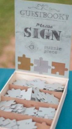 a wooden box filled with puzzle pieces sitting on top of a blue table covered in paper