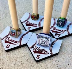 four baseball rings sitting on top of each other in front of three wooden candlesticks