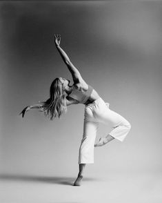 a black and white photo of a woman doing a dance pose with her arms in the air