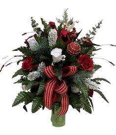 a vase filled with red and white flowers on top of a green planter covered in greenery