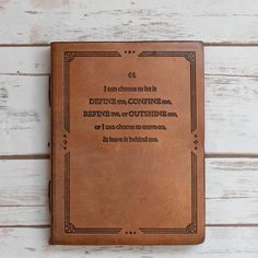 a brown leather book sitting on top of a wooden table