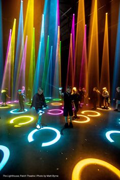 people standing in front of colored lights on the floor at an art museum or show