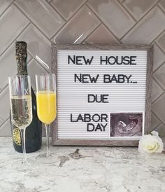 two champagne flutes are next to a sign that says new house, new baby due labor day