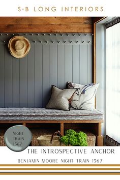 a bench with pillows and hats on it in front of a window, next to a basket