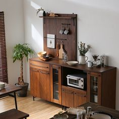 a living room with wooden furniture and potted plants on the shelf next to it