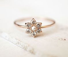 a close up of a ring on a white surface with a flower design in the middle