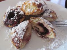 a white plate topped with pastries covered in powdered sugar next to a fork