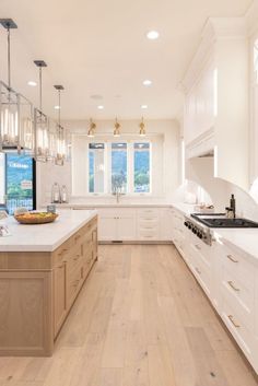 a large kitchen with white cabinets and wood flooring on the countertops, along with an island