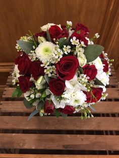 a bouquet of red and white flowers sitting on top of a wooden table