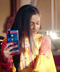 a woman in a yellow dress is looking at her cell phone