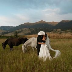 a bride and groom are standing in a field with horses