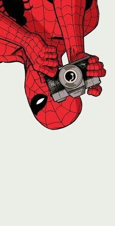 a spiderman holding a camera in his hand and pointing it at the viewer with both hands