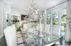 a dining room table with white chairs and chandelier