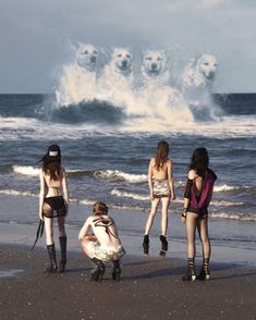 four women standing on the beach with polar bears in the sky above them and one woman kneeling down