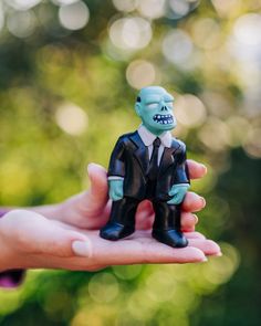 a hand holding a small figurine of a man in a suit