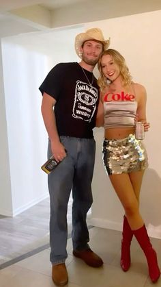 a man standing next to a woman wearing short shorts and cowboy boots in front of a white wall