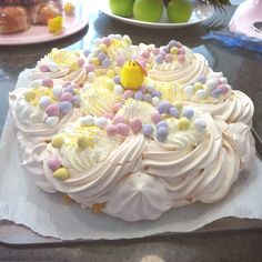 a cake with white frosting and colorful candies on it sitting on a table