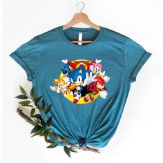 Get ready to race into adventure with this Sonic the Hedgehog t-shirt! Made from soft and breathable fabric, this t-shirt features a bold and colorful design that showcases Sonic in all his speedy glory. The iconic blue character is rendered in high-quality graphics that capture his signature attitude and energy. The shirt is also available in a variety of sizes, making it the perfect fit for gamers of all ages. The design of the shirt is inspired by the classic Sonic games that captured the hea Sonic Tails And Knuckles, Tails And Knuckles, Sonic Tails, Karen Black, Silly Clothes, Ready To Race, Classic Sonic, Signature Look, Star Shirt