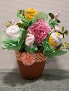 a flower pot filled with lots of different colored flowers on top of a gray surface