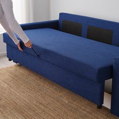 a woman is pulling out the back end of a blue couch