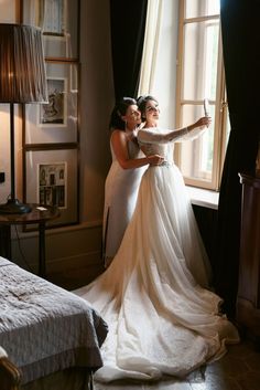 two women in wedding dresses looking out the window