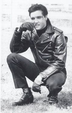 black and white photograph of a man wearing a leather jacket with his hands on his knees