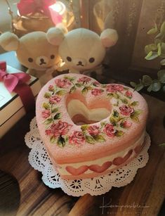 a heart shaped cake sitting on top of a table next to a teddy bear and other decorations