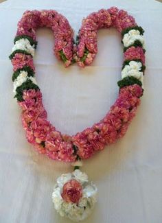 a heart shaped flower arrangement on a table with white and pink flowers in the center