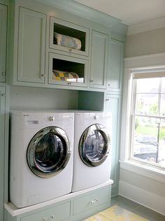 a washer and dryer in a green laundry room with built - in cabinets