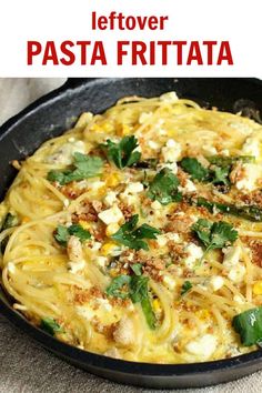 a pan filled with pasta covered in cheese and herbs on top of a table next to a