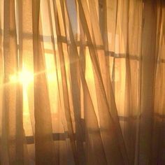 the sun is shining through sheer curtains