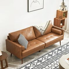 a brown leather couch sitting on top of a white rug