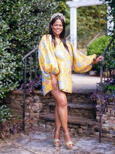 a woman in a yellow robe standing on steps with her hand on her hippie