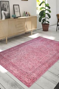 a pink area rug in the middle of a room with white walls and wooden flooring