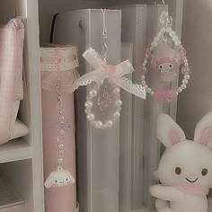 a white stuffed animal sitting next to a pink tube with beads on it's ear