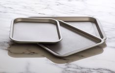 two metal trays sitting on top of a marble counter