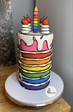 a multi - colored birthday cake with two candles on top