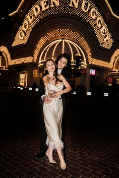 two people posing for a photo in front of the golden nugget at night