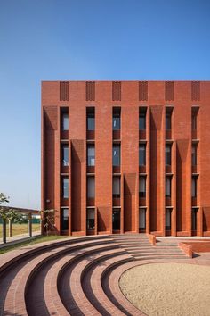 the building is made out of red bricks and has circular steps leading up to it