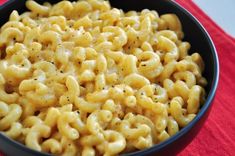 a bowl filled with macaroni and cheese on top of a red table cloth